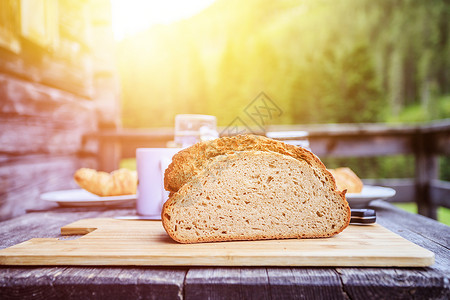 在高山小屋吃早餐的新鲜黑脆面包木板和玻璃瓶的牛奶阳光图片