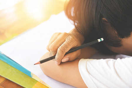 在课堂上学习笔记并使用铅时学习概念的年轻女子学院要求生参加考试决赛并睡在书本上背景图片