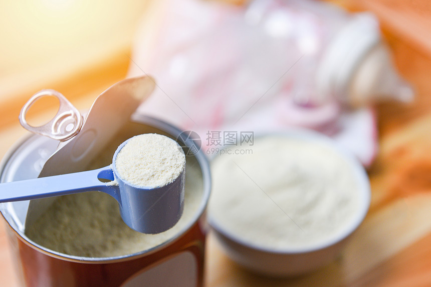 用勺子加罐头的奶粉和木桌背景的婴儿瓶装奶粉图片