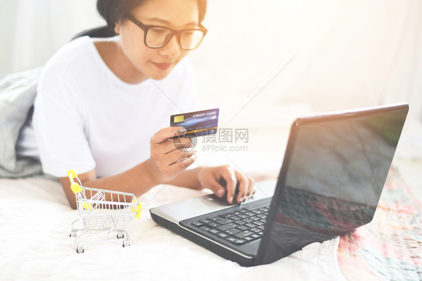 亚洲女手持信用卡使笔记本电脑在线购物图片