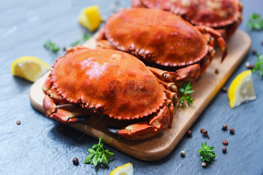 木板上用柠檬在盘子里的烤螃蟹放在黑板顶视线烤海鲜的石蟹上图片