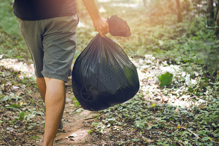 清扫公园男子手在森林里拿着黑色塑料垃圾袋清洁世界拯救地球概念图片