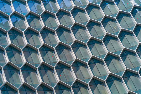 办公室建筑未来技术网络连接概念中六边形窗口的结构蓝玻璃现代建筑设计外观反映市区中心的天空背景图片