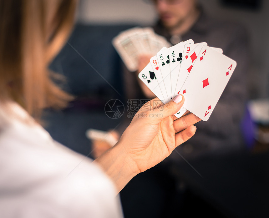 在家里玩牌朋友坐在桌子上女人玩牌男背景模糊图片