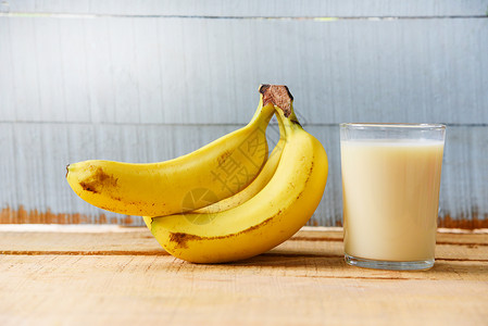 含香蕉水果和以木制的玻璃牛奶和香蕉果制品的健康食背景图片