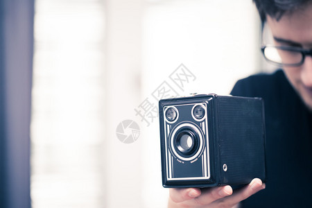 穿黑衬衫的年轻人正在用黑色德国古董相机拍照图片