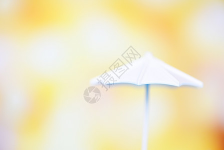 在bokeh和黄色模糊背景上关闭白色雨伞有选择的焦点图片