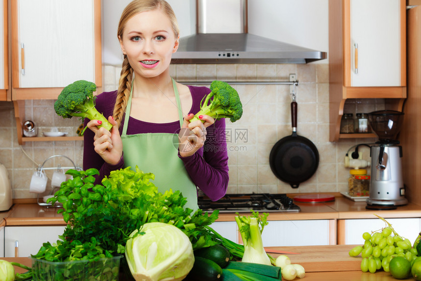 厨房里有许多绿叶蔬菜新鲜农产品的妇女在柜台上年轻家庭主妇手握着西兰花健康饮食烹饪素品饮和人的概念厨房里的妇女手握着绿色蔬菜西兰花图片
