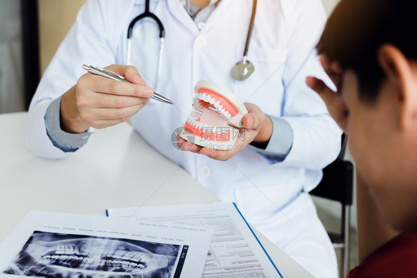亚洲牙医用笔指着假描述齿问题图片