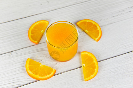 玻璃中的橙汁和木桌上新鲜橙子水果片图片