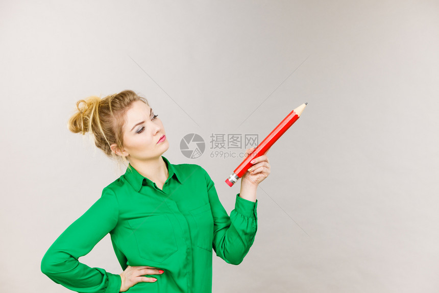 深思熟虑的女学生或教师提出一个想法持有大红铅笔工作室拍摄灰色女混淆思考手头拿着大铅笔图片