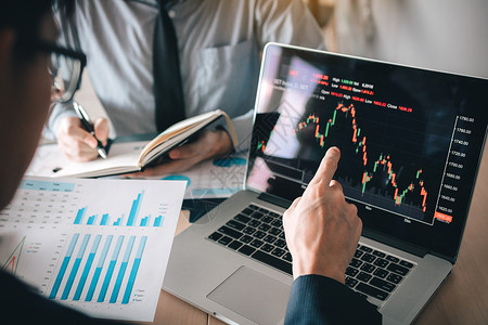 投资者指出膝上型计算机拥有投资信息股票市场和合作伙伴记录分析业绩数据背景图片