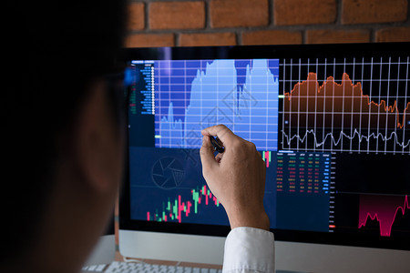 电脑屏幕图雇员们用指向电脑屏幕的笔分析股票市场图背景