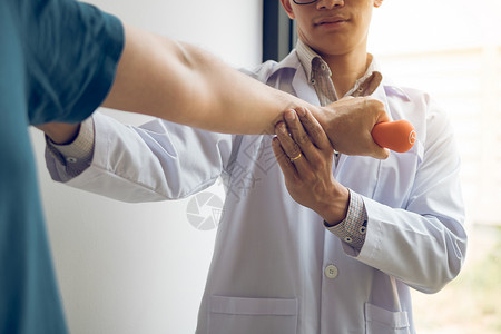 亚洲年轻男理疗师帮助病人在办公室里举起哑铃锻炼物理治疗师高清图片素材