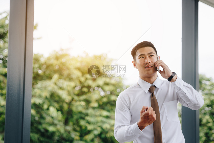 年轻的亚洲英俊商人在电话和工作快乐上交谈图片