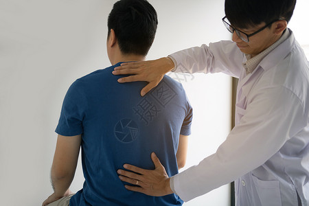 理疗师用手检查病人的背部骨质疏松症高清图片素材