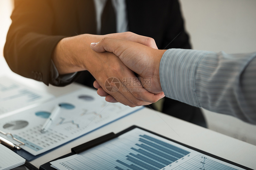 企业伙伴关系为签署公司财务报表告而握手并在办公室多年赚取利润图片