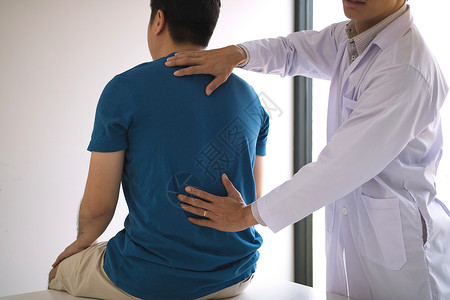 理疗师用手检查病人的背部医学的高清图片素材