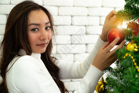 年轻的青少女孩装饰圣诞树准备和男朋友一起过圣诞节图片