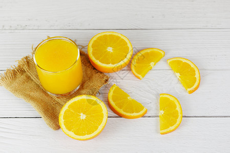 玻璃中的橙汁和木制桌上的新鲜橙子水果片图片