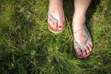 在绿草红指甲油上贴翻的拖鞋或凉红色指甲油图片