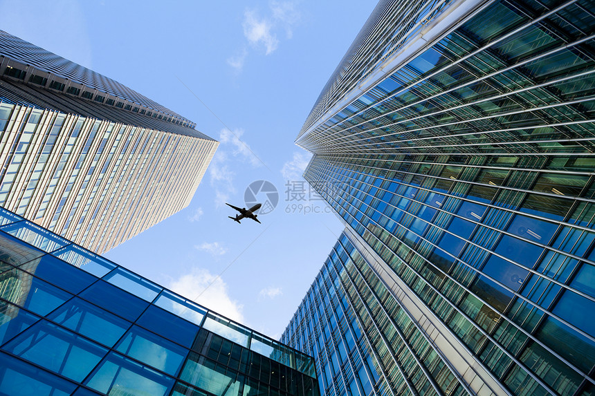 一架飞机在高楼大厦上空飞行图片