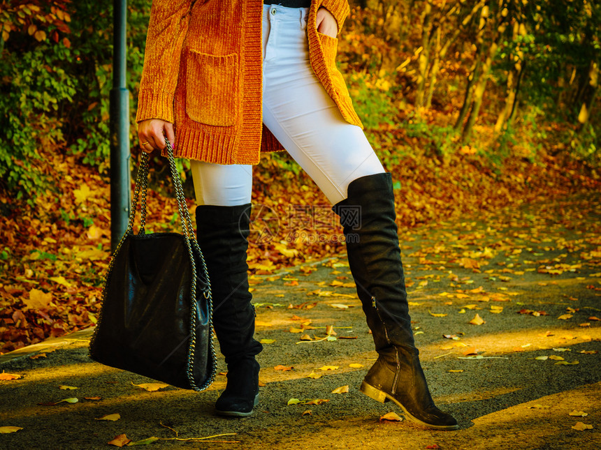 穿着长橙色温暖的羊毛衫难以辨认妇女秋季时装在公园散步的女图片