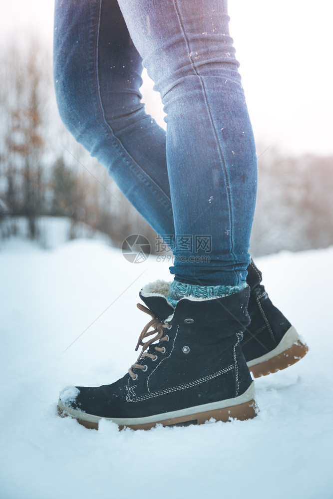 穿蓝色牛仔裤的女孩在冬季腿和鞋子上徒步旅行图片