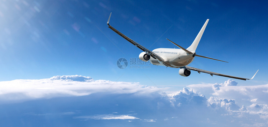 白色客机飞越蓝天白云上空图片