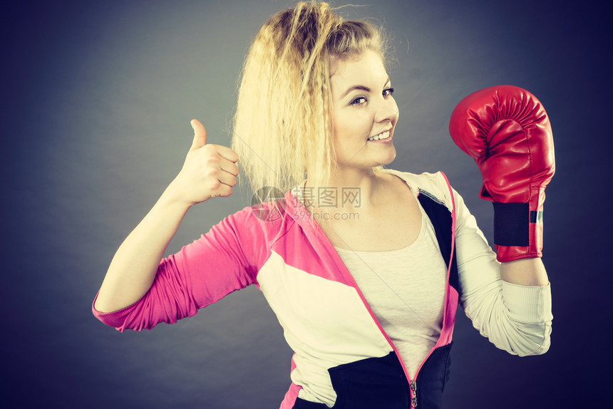 身着红拳击手套的运动快乐妇女展示出正面的格萨特大拇指图片