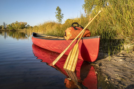 红色独木舟板和湖岸防水的帆船瀑布风景图片