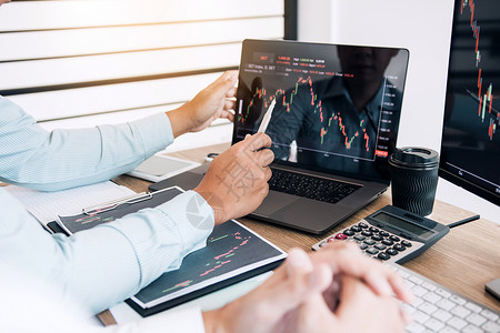 两个伙伴投资者讨论共同合作正在分析办公司计算机屏幕上的股票图表背景图片