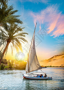 古代帆船尼罗河和在阿斯旺日落时的渔船背景