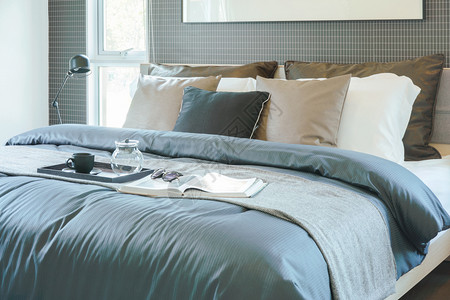 茶叶书和太阳镜的托盘放在现代经典风格室内卧的床上图片