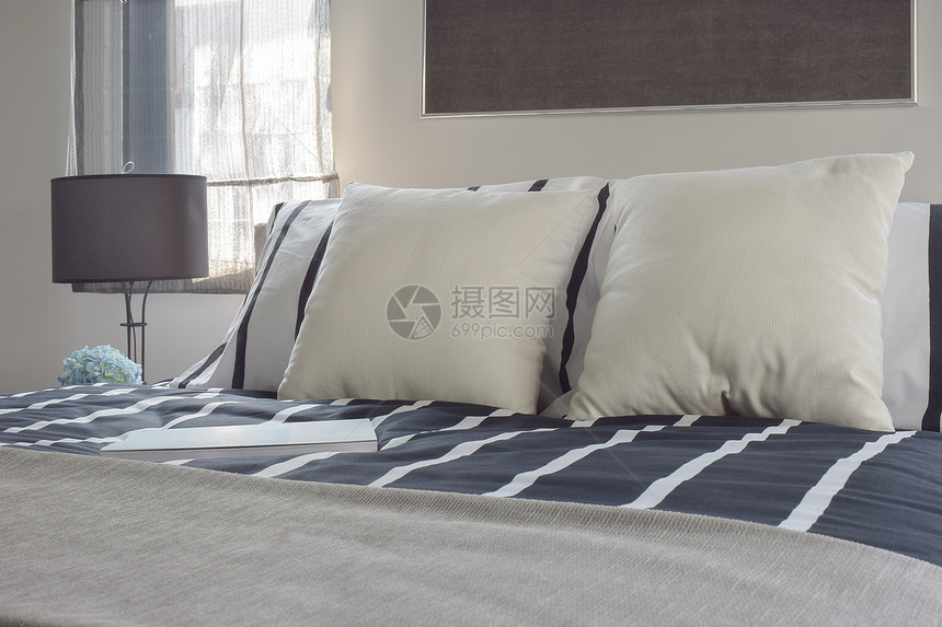 在现代式卧室用深蓝色带条纹毯子铺在床上的脱白色和条纹枕头图片