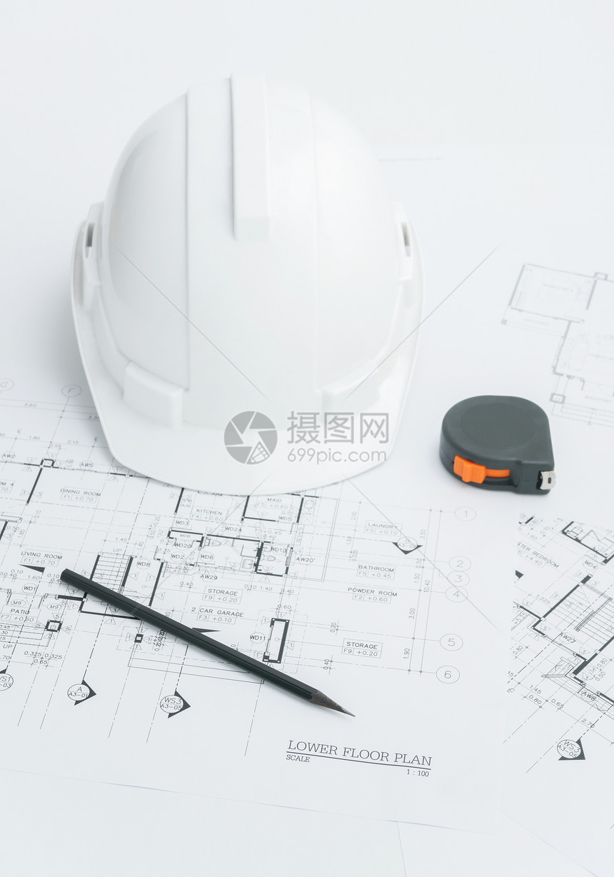 建筑师工作场所建筑蓝图上面有测量胶带安全头盔和桌面上的工具图片