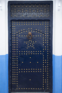 在摩洛哥Asilah的梅迪纳用蓝色油漆的有金装饰蓝木制门背景图片
