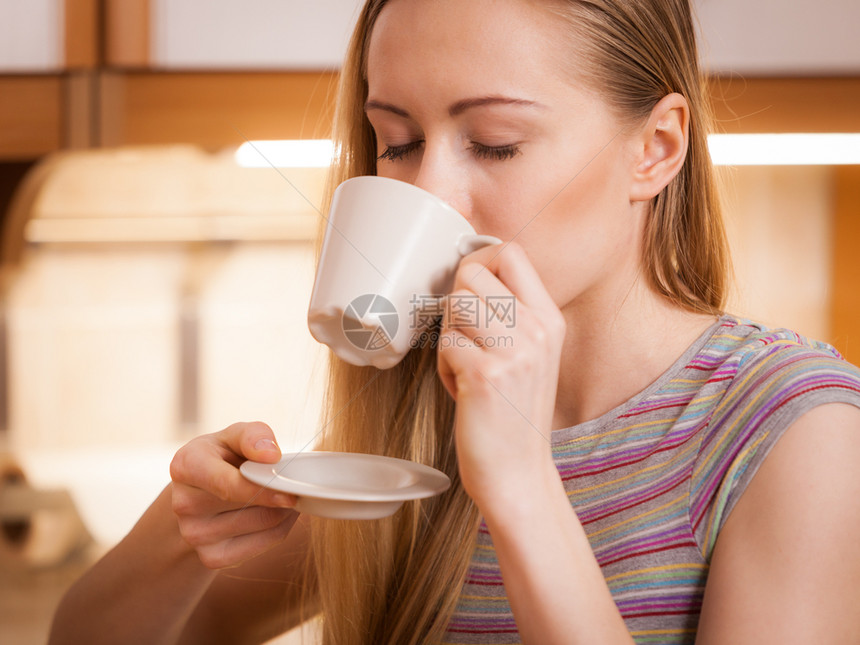 快乐的女士站在厨房喝着咖啡的茶享受她放松的空闲时间快乐的女士喝着咖啡茶图片