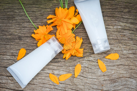 木材背景上黄花和用于美容治疗和温泉有机最低程度生活方式的天然乳液瓶图片