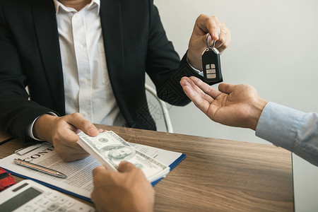 客户和汽车销售代理人交换现金和车钥匙图片