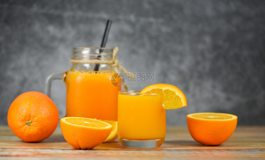 玻璃罐中的橙汁和木制桌子上新鲜橙水果切片图片