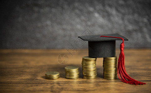 奖学金教育概念对用于木桌黑背景赠款教育的硬币储蓄实行毕业上限图片