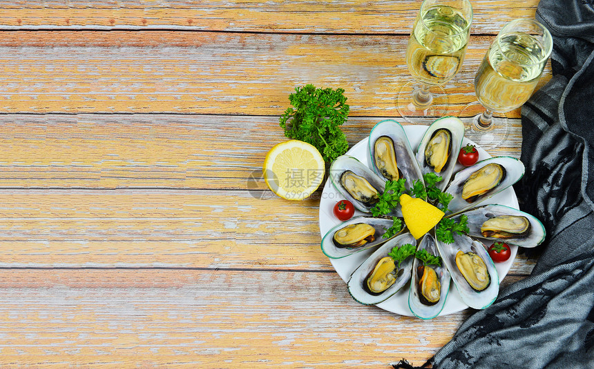 餐桌布置中含有药草和柠檬面柠檬的贝在白盘上供应的蒸汽贝和葡萄酒杯餐桌饮中美味的海鲜酱图片