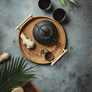 传统亚洲茶叶仪式安排铁茶壶杯干绿叶姜树和热带叶深水泥底平地复制空间图片