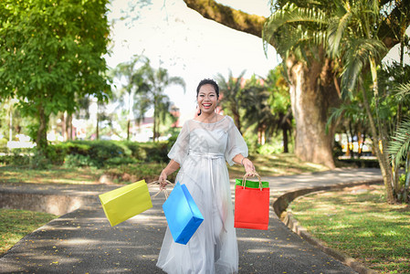 女在户外购物并手持袋亚裔妇女在公园中欢笑和快乐图片