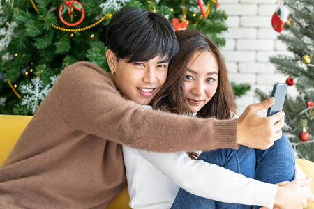 年轻成青少夫妇为庆祝圣诞节在带有树装饰的起居室拍摄自图片