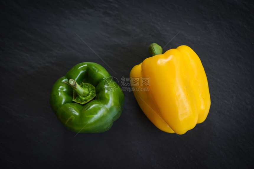 黑暗背景死生果和蔬菜上的新鲜黄青甜辣椒图片