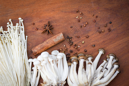 佩斯基奇Enoki或GoldenNineleMushroom和ShimejiMushroom木本上配有草药和香料背景