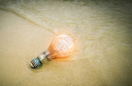 海滩上概念灯泡沙滩垃圾上橙色照明海滩停止污染拯救地球图片