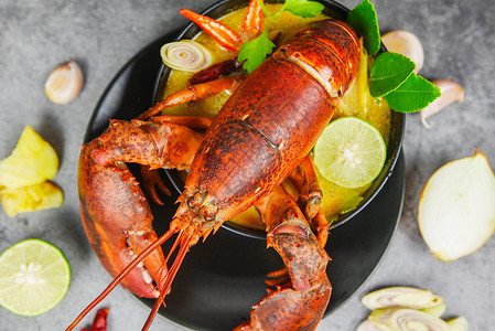 红龙虾辣汤碗煮的海鲜加上龙虾晚饭桌和黑盘泰餐上的香料成分TomYumKung背景图片